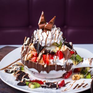 side view of layered fruit dessert with whipped cream and chocolate syrup on a plate